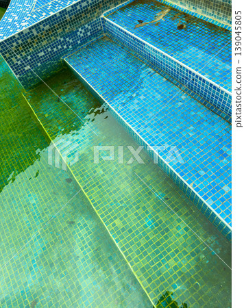 Water steps in a tiled pool showing different shades of blue and green with reflections in calm water at a public area during daylight Water steps in a tiled pool showing different shades of blue and green with reflections in calm water at a public area during daylight 139045805