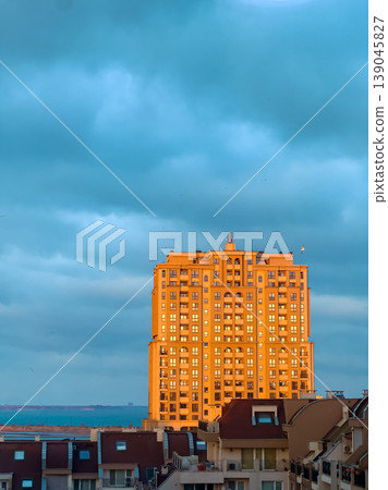 Building with sunset light, clouds, and ocean view in the background during evening hours Building with sunset light, clouds, and ocean view in the background during evening hours 139045827