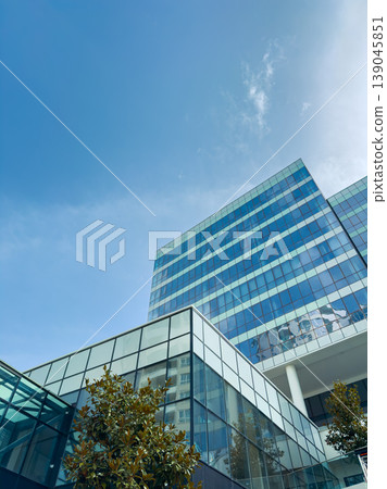 Modern building with glass facade and clear blue sky in an urban setting during daytime Modern building with glass facade and clear blue sky in an urban setting during daytime 139045851