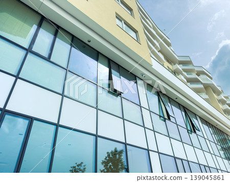 Building with large glass windows during the day in a modern urban area with clear skies above Building with large glass windows during the day in a modern urban area with clear skies above 139045861