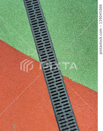 Colorful rubber flooring with drainage in a playground area during daytime near a park Colorful rubber flooring with drainage in a playground area during daytime near a park 139045866