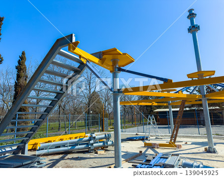 Construction site shows metal framework and stairs for a new structure in a park under a clear blue sky in the afternoon 139045925