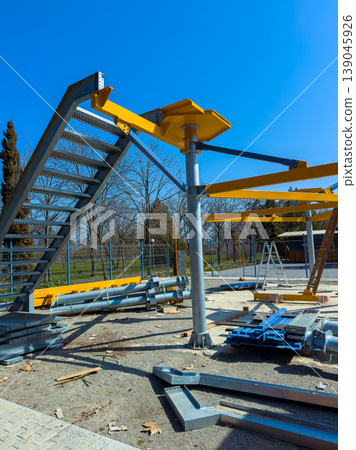 Construction site shows metal structures being assembled in a park area on a sunny day 139045926