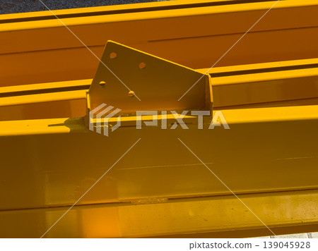 Construction equipment is resting under the sunlight in a work area during midday hours in a bright yellow color Construction equipment is resting under the sunlight in a work area during midday hours in a bright yellow color 139045928