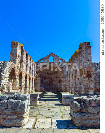 Ancient stone ruins stand under a clear blue sky in a historic location with visible arches and walls from past architecture Ancient stone ruins stand under a clear blue sky in a historic location with visible arches and walls from past architecture 139045980