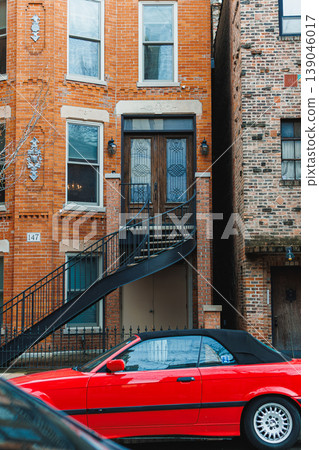 Stairs and a red car outside a brick building in an urban neighborhood during the day in winter Stairs and a red car outside a brick building in an urban neighborhood during the day in winter 139046017