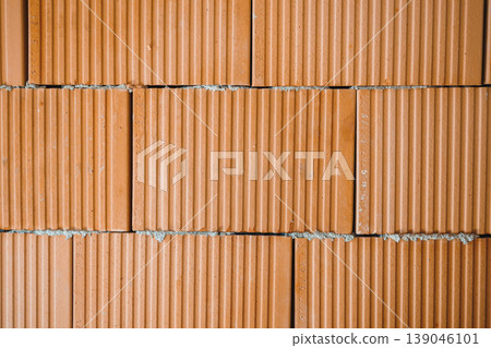 Construction workers build a wall using red bricks in a residential area during daylight hours 139046101