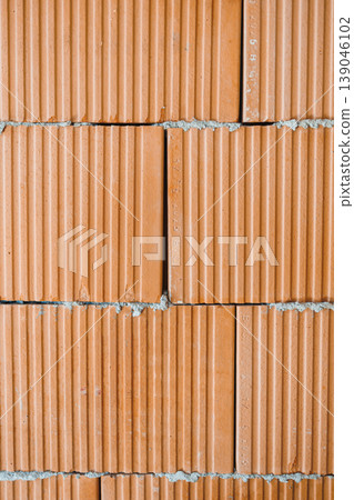 Construction activity shows a wall made of red clay bricks stacked in a structured pattern across a workspace Construction activity shows a wall made of red clay bricks stacked in a structured pattern across a workspace 139046102