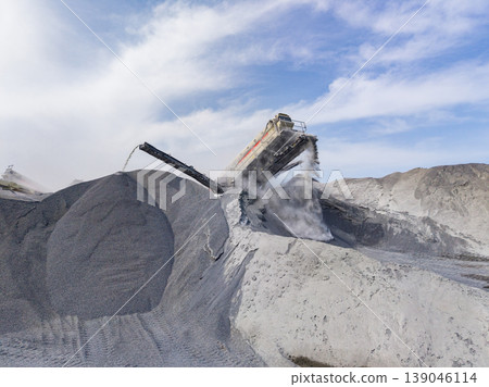 Granite quarry shows large machine working to move materials during bright daytime hours in a busy scene of extraction and processing Granite quarry shows large machine working to move materials during bright daytime hours in a busy scene of extraction and processing 139046114
