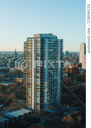 View of a tall building among cityscape showing urban life, clear sky and surrounding area during late afternoon 139046128