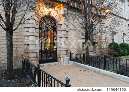 Entrance to a building in a city with plants visible inside during evening hours 139046160