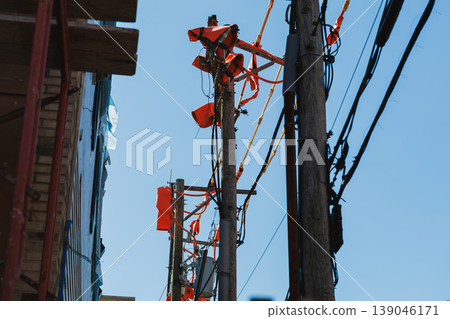 Electric poles with bright orange tape above the street in a city setting during the daytime Electric poles with bright orange tape above the street in a city setting during the daytime 139046171