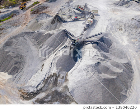 Mining activity occurs at a large granite quarry site during daylight hours showing machinery at work transporting materials Mining activity occurs at a large granite quarry site during daylight hours showing machinery at work transporting materials 139046220