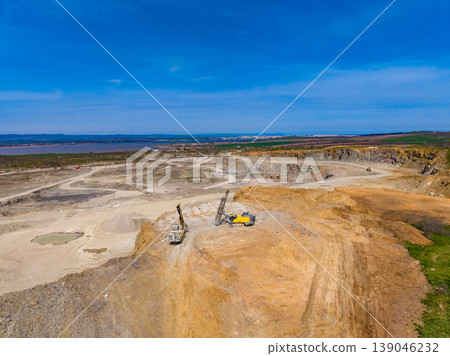 Granite quarry operation in a large excavation site with machinery working under a clear sky 139046232