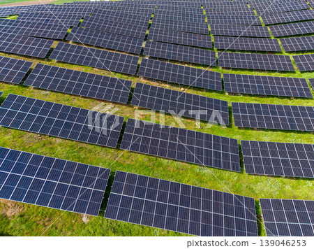 Solar panels cover a large land area and generate clean energy in an open field on a sunny day 139046253