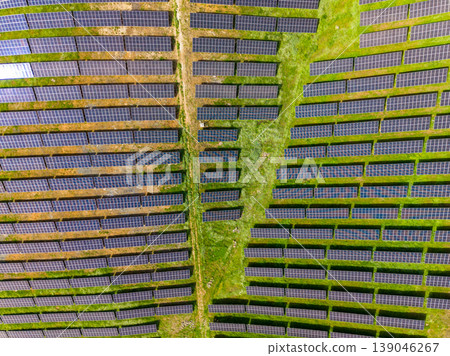 Large solar panel field in a rural area during bright daylight with green grass and uniform rows of panels Large solar panel field in a rural area during bright daylight with green grass and uniform rows of panels 139046267