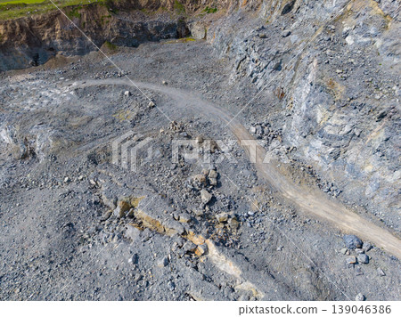 Granite quarry site with rough terrain and a winding road leading through the rocky landscape during daylight hours Granite quarry site with rough terrain and a winding road leading through the rocky landscape during daylight hours 139046386