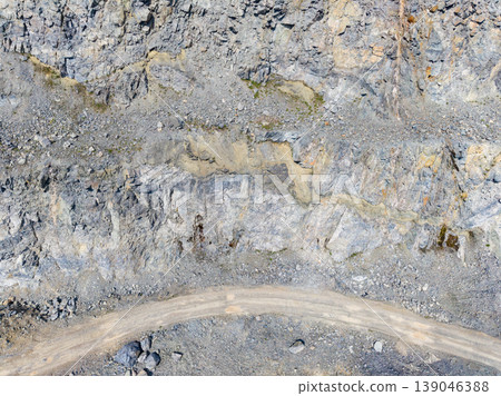 Granite quarry with exposed rock layers and a winding road in a mining site during daylight hours Granite quarry with exposed rock layers and a winding road in a mining site during daylight hours 139046388