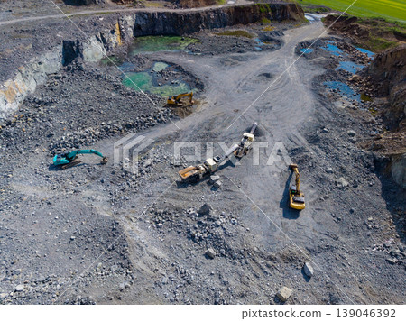 Granite quarry site with machinery and extraction work in operation at a mining location during daytime 139046392