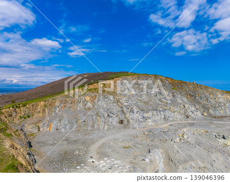 Operations at a granite quarry situated on a hillside during a clear day with scattered clouds in the sky and a serene landscape surrounding the site Operations at a granite quarry situated on a hillside during a clear day with scattered clouds in the sky and a serene landscape surrounding the site 139046396