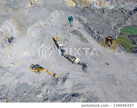 Activity of workers at granite quarry showing machines and tools used at the site for mining and extraction of stone materials in a large open area Activity of workers at granite quarry showing machines and tools used at the site for mining and extraction of stone materials in a large open area 139046397