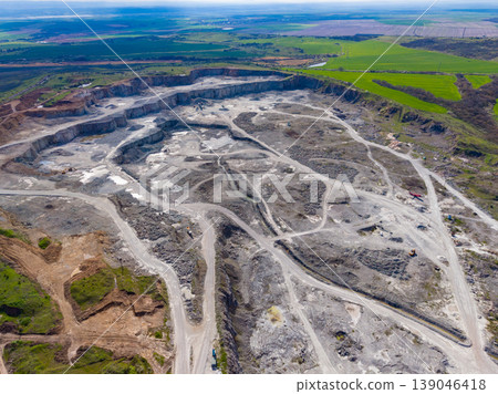 Granite quarry site showing active stone extraction near a countryside area with green fields in the background Granite quarry site showing active stone extraction near a countryside area with green fields in the background 139046418