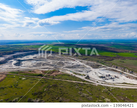 Granite quarry operation in a rural area with green fields and clear sky during the day 139046421