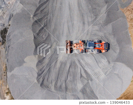 Heavy machinery working in a granite quarry during daylight hours moving and processing stone materials and granite Heavy machinery working in a granite quarry during daylight hours moving and processing stone materials and granite 139046433