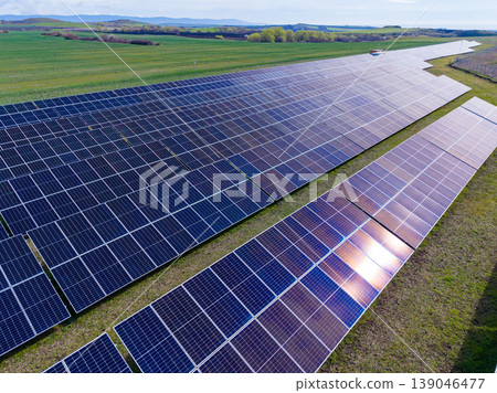 Solar panels cover a large field in sunlight, showcasing renewable energy production in a rural area during daytime hours 139046477