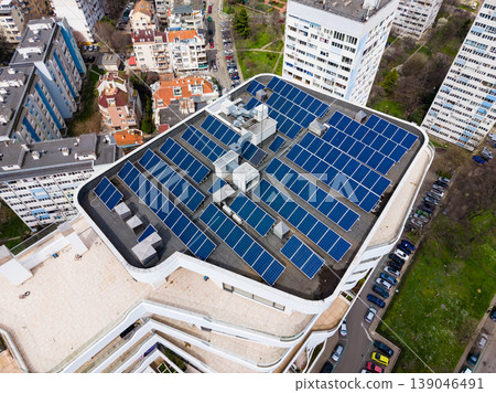 Solar panels cover the rooftop of a modern building in a city area during daylight, showing an effort towards renewable energy and sustainability in urban spaces Solar panels cover the rooftop of a modern building in a city area during daylight, showing an effort towards renewable energy and sustainability in urban spaces 139046491