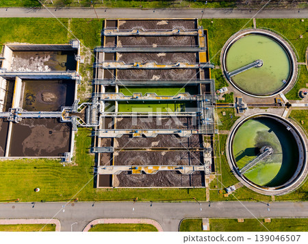 Water treatment facility operates with large tanks and processing equipment in an urban area during daylight hours Water treatment facility operates with large tanks and processing equipment in an urban area during daylight hours 139046507