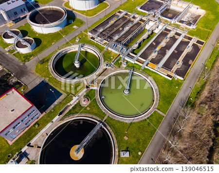 Wastewater treatment facility shows large tanks and machinery during daytime in a rural area 139046515