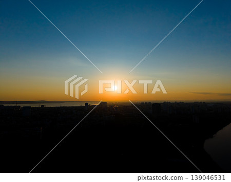 Set sun over city skyline near water in the evening with clear sky and distant buildings visible in the horizon 139046531