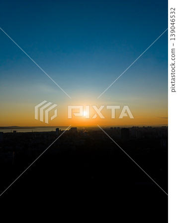 Sunset view over city skyline with buildings and water in distance during evening hours showcasing warm colors in the sky 139046532