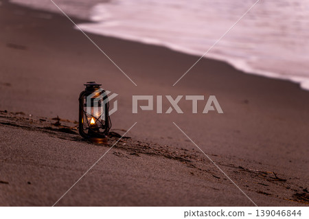 An antique hurricane lantern placed on the beach at dusk. An antique hurricane lantern placed on the beach at dusk. 139046844