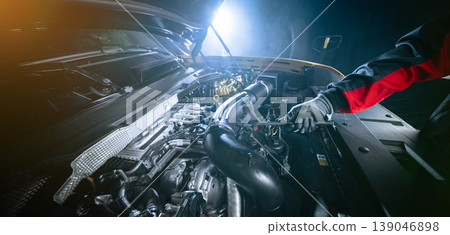 Mechanic repairing car engine in workshop, using tools with dramatic lighting. Automotive maintenance and professional service concept. Mechanic repairing car engine in workshop, using tools with dramatic lighting. Automotive maintenance and professional service concept. 139046898