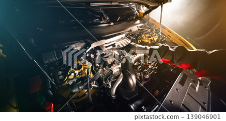 Mechanic repairing car engine in workshop, using tools with dramatic lighting. Automotive maintenance and professional service concept. Mechanic repairing car engine in workshop, using tools with dramatic lighting. Automotive maintenance and professional service concept. 139046901