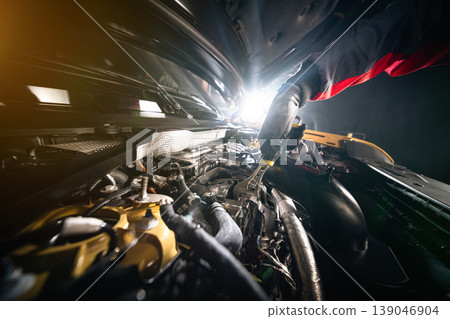Mechanic repairing car engine in workshop, using tools with dramatic lighting. Automotive maintenance and professional service concept. 139046904