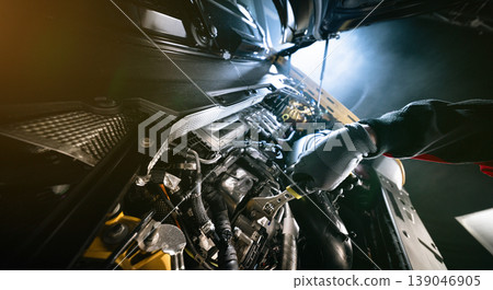 Mechanic repairing car engine in workshop, using tools with dramatic lighting. Automotive maintenance and professional service concept. 139046905