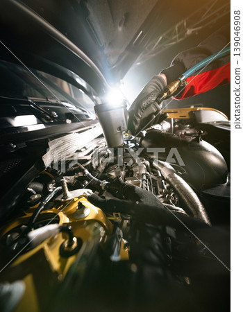 Mechanic repairing car engine in workshop, using tools with dramatic lighting. Automotive maintenance and professional service concept. Mechanic repairing car engine in workshop, using tools with dramatic lighting. Automotive maintenance and professional service concept. 139046908