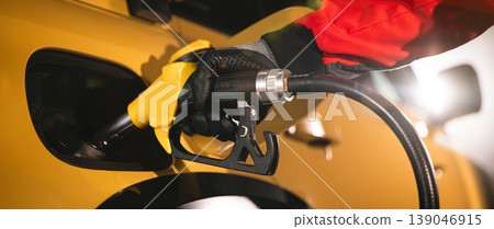 Close-up of fuel nozzle inserted into car tank. Refueling process, automotive energy, transportation and fuel service concept with dramatic lighting. Close-up of fuel nozzle inserted into car tank. Refueling process, automotive energy, transportation and fuel service concept with dramatic lighting. 139046915