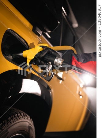 Close-up of fuel nozzle inserted into car tank. Refueling process, automotive energy, transportation and fuel service concept with dramatic lighting. Close-up of fuel nozzle inserted into car tank. Refueling process, automotive energy, transportation and fuel service concept with dramatic lighting. 139046917