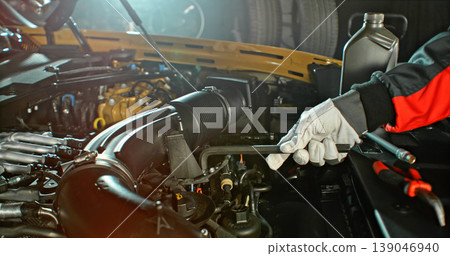 Mechanic repairing car engine in workshop, using tools with dramatic lighting. Automotive maintenance and professional service concept. Mechanic repairing car engine in workshop, using tools with dramatic lighting. Automotive maintenance and professional service concept. 139046940