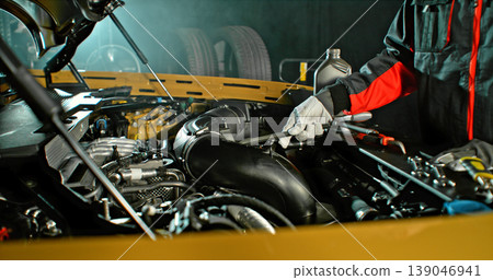Mechanic repairing car engine in workshop, using tools with dramatic lighting. Automotive maintenance and professional service concept. Mechanic repairing car engine in workshop, using tools with dramatic lighting. Automotive maintenance and professional service concept. 139046941
