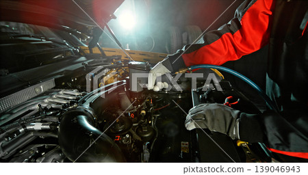 Mechanic repairing car engine in workshop, using tools with dramatic lighting. Automotive maintenance and professional service concept. 139046943