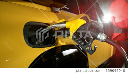Close-up of fuel nozzle being removed from car tank. Refueling process, automotive energy and fuel service concept with dramatic lighting. Close-up of fuel nozzle being removed from car tank. Refueling process, automotive energy and fuel service concept with dramatic lighting. 139046948