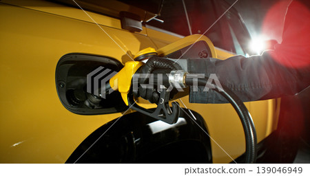 Close-up of fuel nozzle inserted into car tank. Refueling process, automotive energy, transportation and fuel service concept with dramatic lighting. Close-up of fuel nozzle inserted into car tank. Refueling process, automotive energy, transportation and fuel service concept with dramatic lighting. 139046949