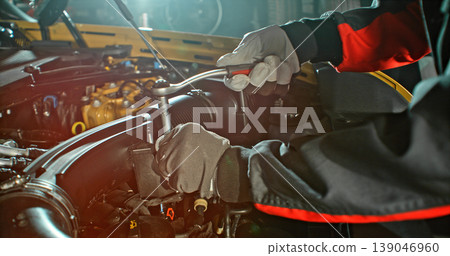 Mechanic repairing car engine in workshop, using tools with dramatic lighting. Automotive maintenance and professional service concept. 139046960