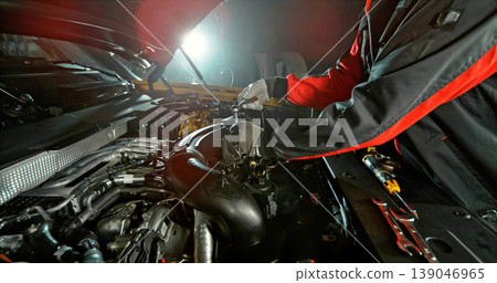 Mechanic repairing car engine in workshop, using tools with dramatic lighting. Automotive maintenance and professional service concept. Mechanic repairing car engine in workshop, using tools with dramatic lighting. Automotive maintenance and professional service concept. 139046965