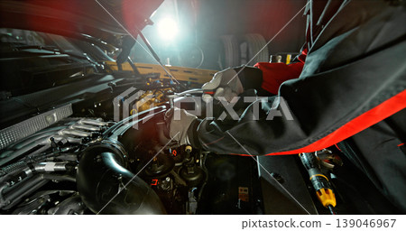 Mechanic repairing car engine in workshop, using tools with dramatic lighting. Automotive maintenance and professional service concept. 139046967